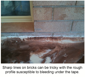 An epoxy floor coating bleeding underneath a tape line on bricks.