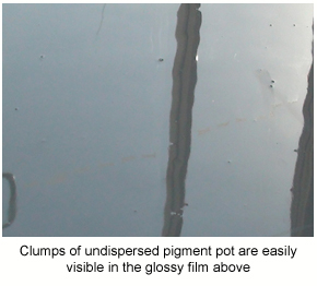 Clumps of undispersed pigment pot visible in a solventless epoxy film.